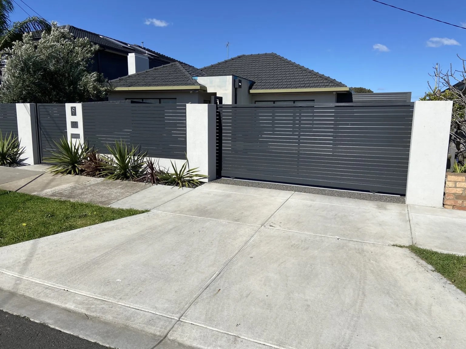 Dark grey aluminum slat fence with sliding driveway gate in League City TX