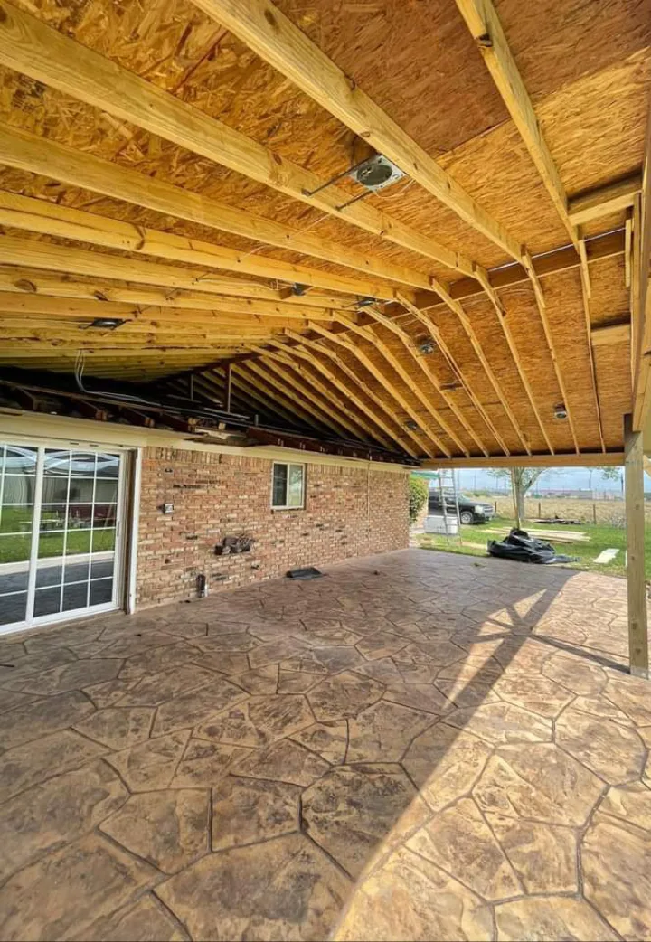 Covered patio roof framing over a finished stone-patterned patio in Pearland TX