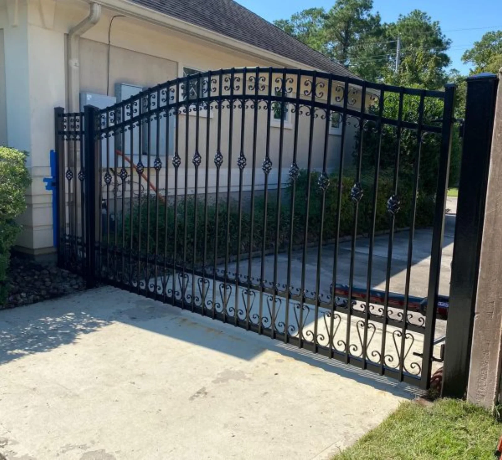 Ornate wrought iron arched driveway gate with scrollwork in Pearland TX