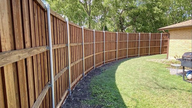 Curved cedar privacy fence run on steel posts in a Friendswood TX backyard